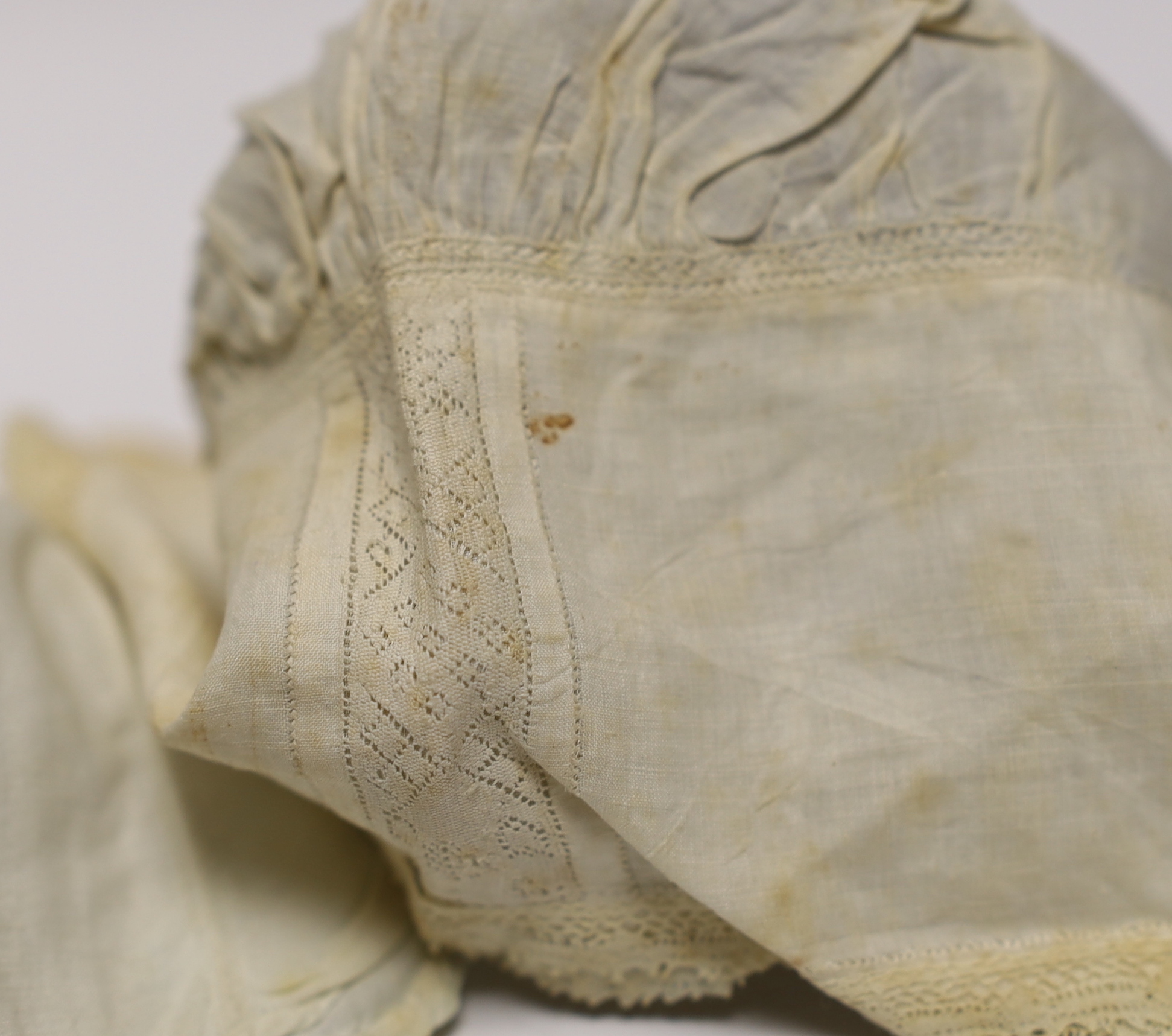 An early 18th century Hollie point insertion baby’s linen vest, three baby bonnets with Hollie point insertions and an early 18th century pair of Flemish bobbin lace lappets, a partly finished needlepoint length of lace,
